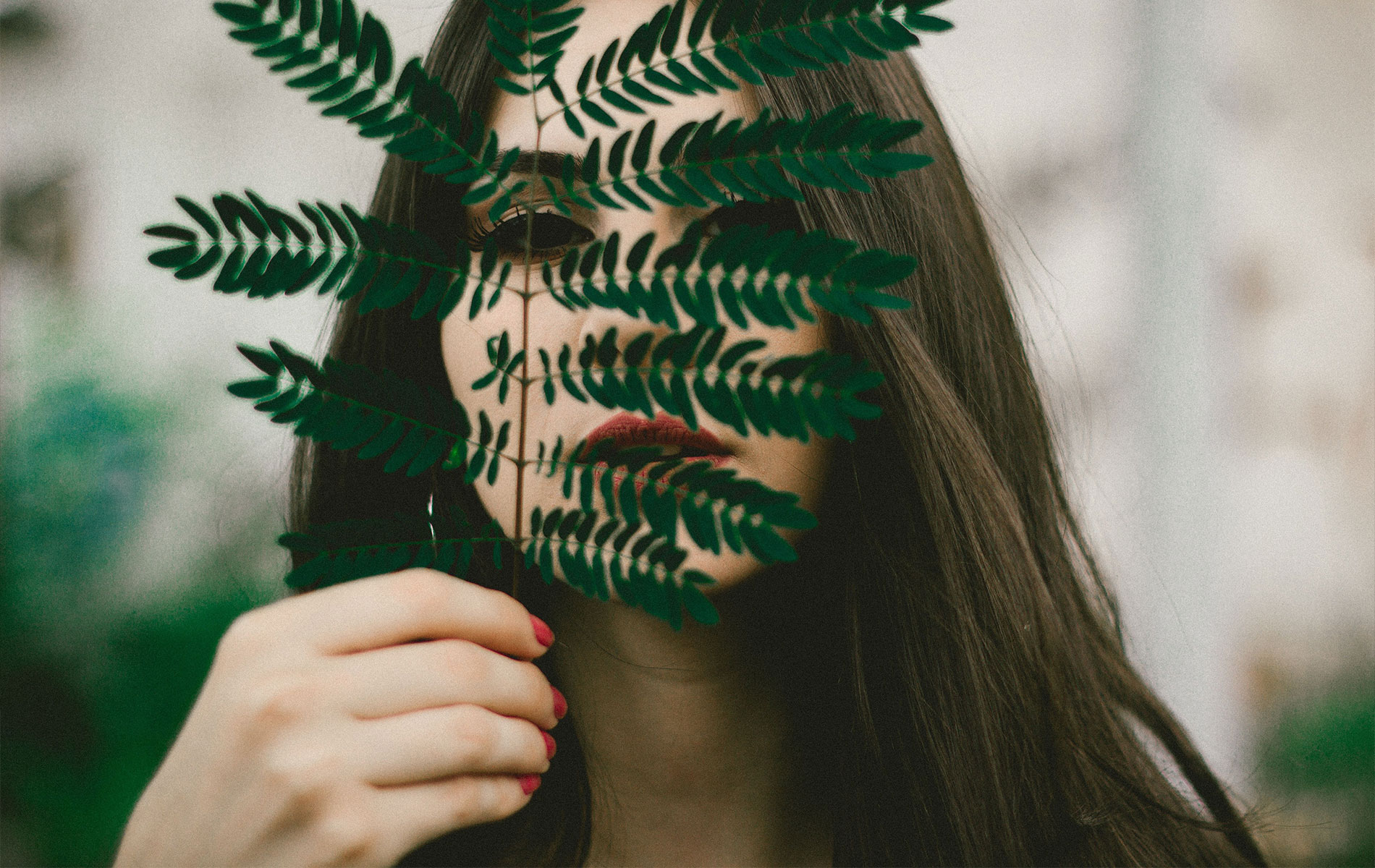 Woman holding a leaf in front of her face